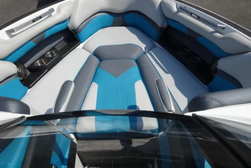 Slide: The Image of 2016 Malibu 25 LSV boat interior with blue and gray seating, cup holders, and speakers. - 4