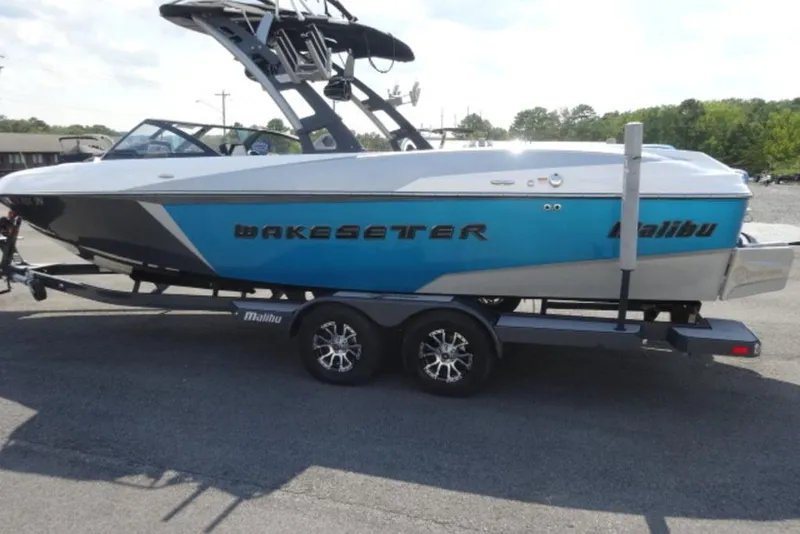 Slide: The Image of 2016 Malibu 25 LSV Wakesetter boat on trailer, blue and white design. - 7