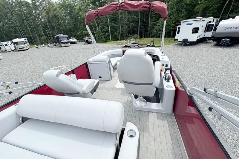 Slide: The Image of 2022 Bentley Pontoons 223 Elite interior with white seating and red accents, parked outdoors. - 19