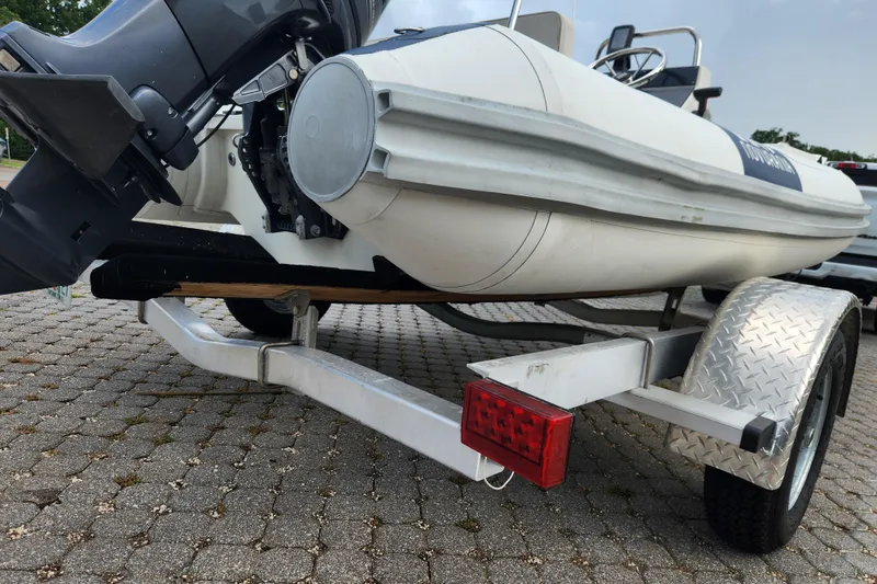 Slide: The Image of 2019 Novurania DL 400 boat on trailer, featuring outboard motor and diamond plate fender. - 34