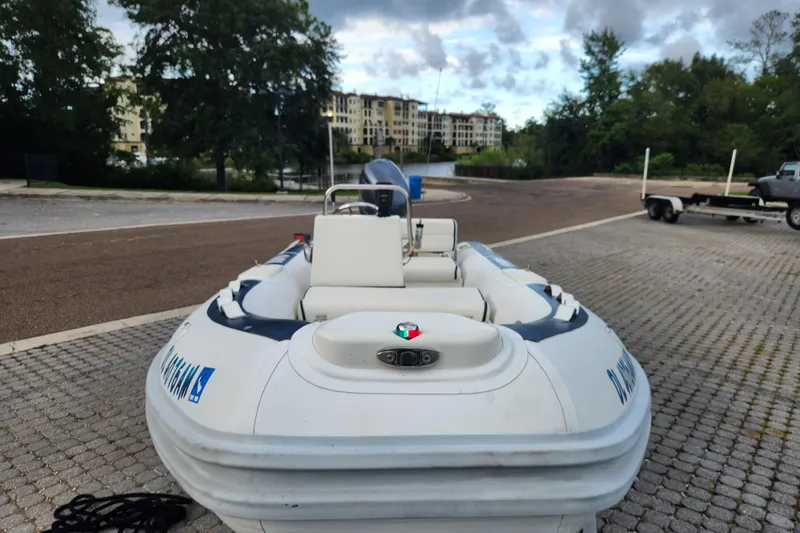 Slide: The Image of 2019 Novurania DL 400 boat on a paved dock with trees and buildings in the background. - 5