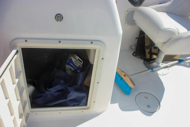 Slide: The Image of 2013 Hurricane SunDeck Sport 188 OB boat storage compartment with cleaning supplies and seat. - 14