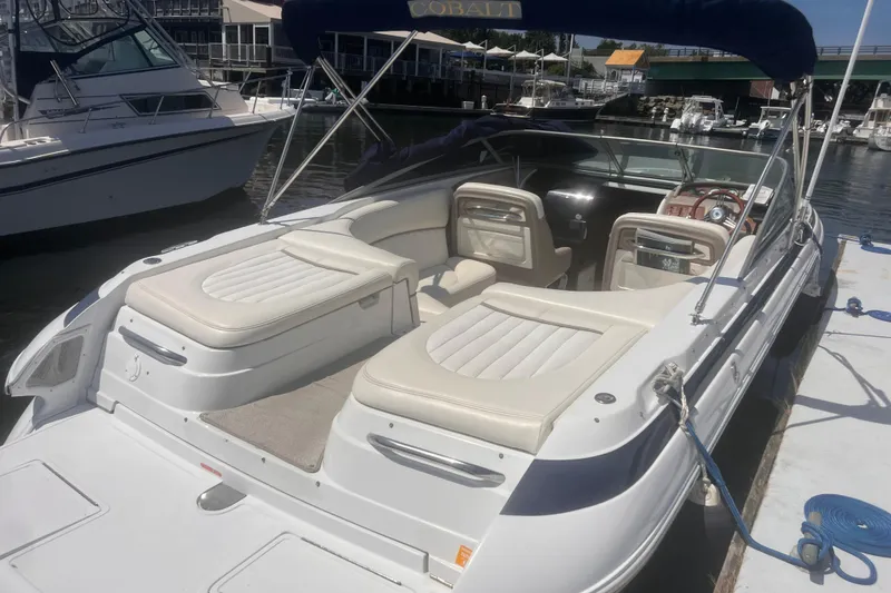 Slide: The Image of 2003 Cobalt 263 boat docked, featuring white seating and a blue canopy. - 14