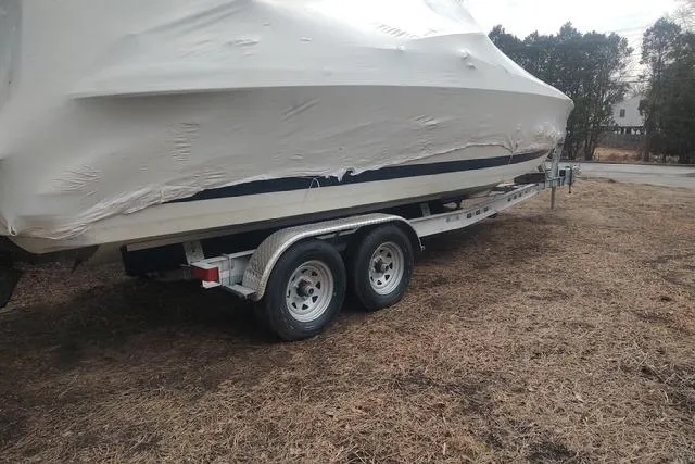 Slide: The Image of 2003 Cobalt 263 boat covered on a trailer, parked on dry grass. - 33