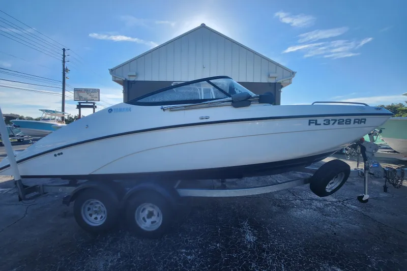 The Image of 2018 Yamaha Boats SX210 on trailer, parked outdoors under clear sky. - 0