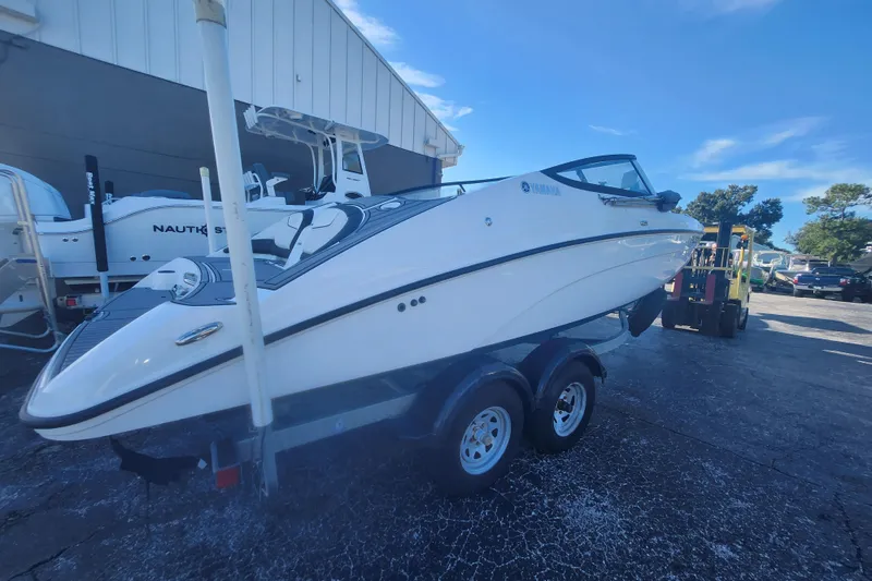 Slide: The Image of 2018 Yamaha Boats SX210 on trailer, parked outdoors under clear blue sky. - 2