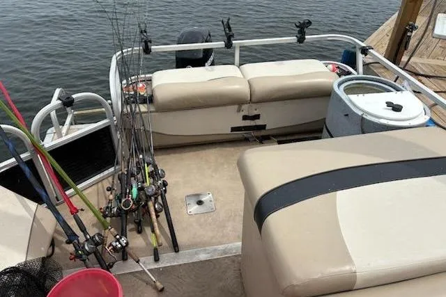 Slide: The Image of 2013 Sun Tracker Fishing Barge 22 with fishing rods and seating on a calm lake. - 5