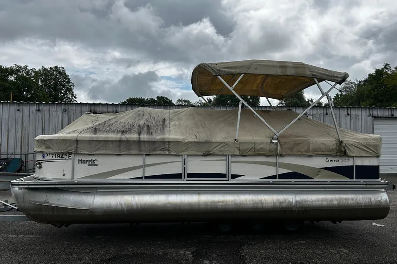 The Image of 2009 Harris Cruiser 220 pontoon boat with canopy, parked outdoors under cloudy skies. - 1