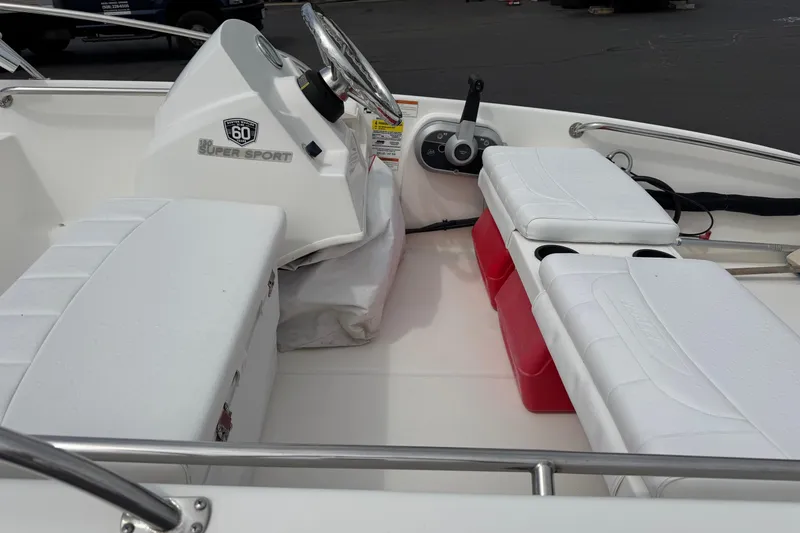 Slide: The Image of 2018 Boston Whaler 130 Super Sport interior with white seating and steering console. - 6