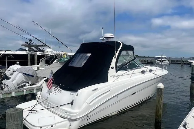 The Image of 2006 Sea Ray 300 Sundancer docked at marina, featuring sleek design and black canopy. - 0