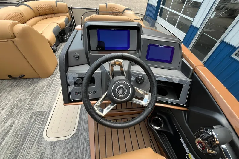 Slide: The Image of 2025 Avalon Catalina Quad Lounger Shift Windshield boat dashboard with dual screens and steering wheel. - 24