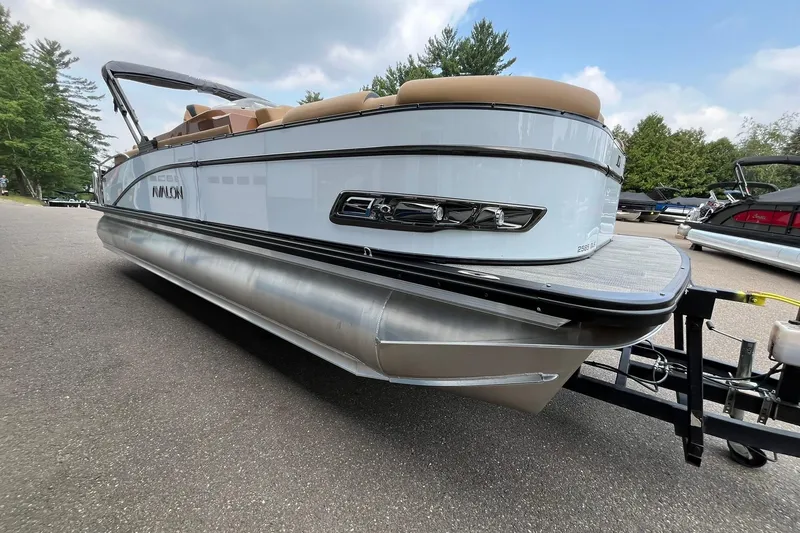 Slide: The Image of 2025 Avalon Catalina Quad Lounger Shift Windshield pontoon boat on trailer, parked outdoors. - 5