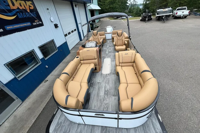 Slide: The Image of 2025 Avalon Catalina Quad Lounger Shift Windshield pontoon boat with tan seating, docked near a marine shop. - 8