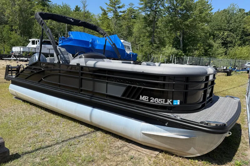 Slide: The Image of 2024 Bennington 23LSB pontoon boat on grass, surrounded by trees and other boats. - 0