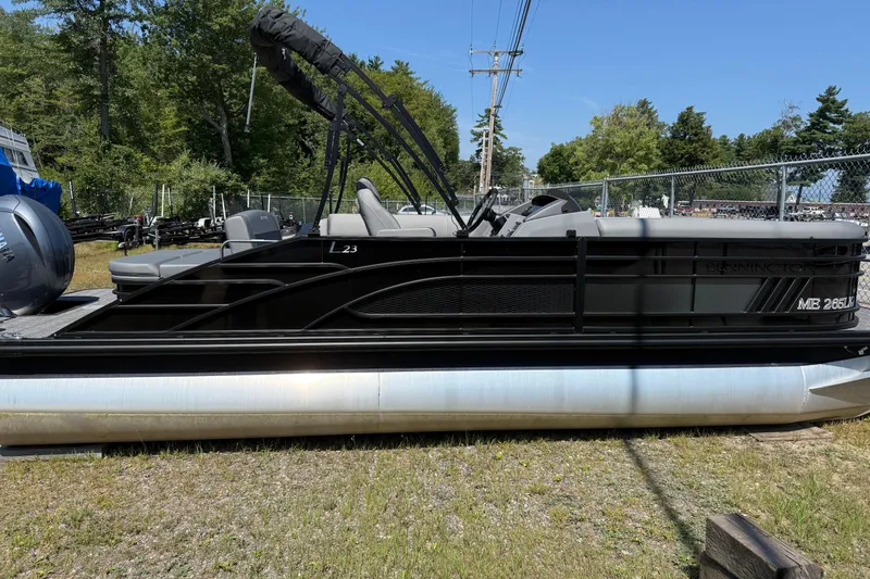 Slide: The Image of 2024 Bennington 23LSB pontoon boat in a yard, featuring sleek black design. - 1
