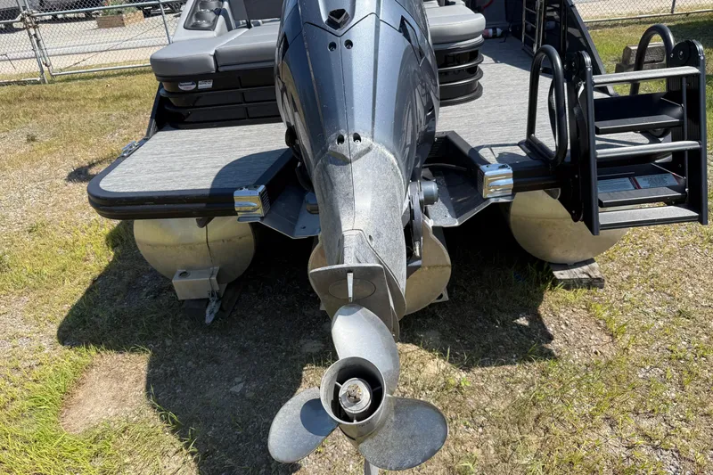 Slide: The Image of 2024 Bennington 23LSB pontoon boat with outboard motor and ladder, parked on grass. - 11