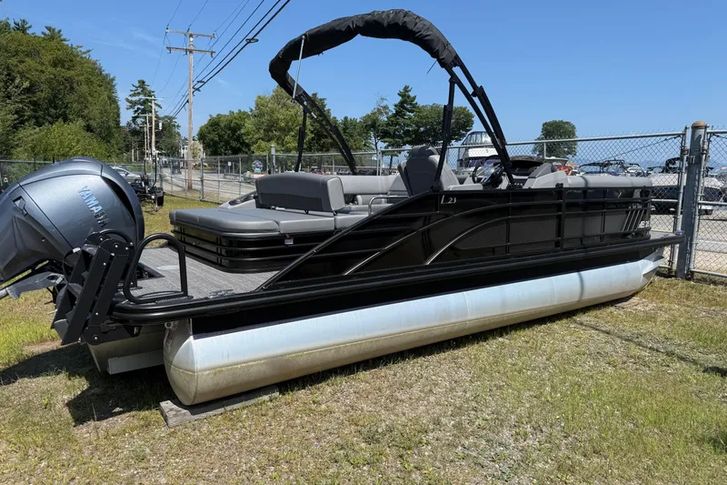Slide: The Image of 2024 Bennington 23LSB pontoon boat with Yamaha engine, parked on grass near a fence. - 13