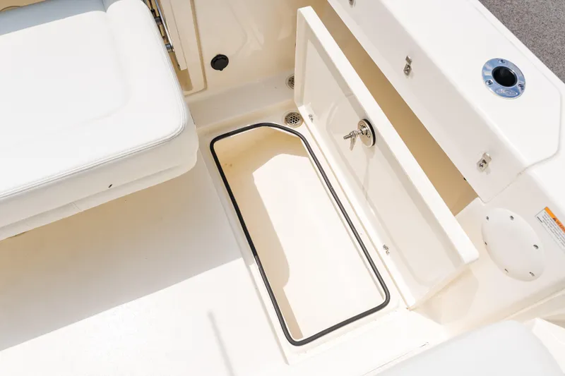 Slide: The Image of 2023 Cobia 240 Dual Console boat interior with white seating and storage compartments. - 15