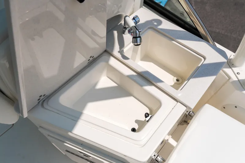 Slide: The Image of 2023 Cobia 240 Dual Console boat storage compartments with open drawers and tackle boxes. - 8