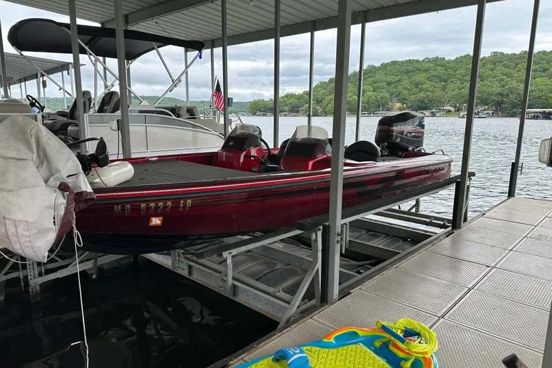 Slide: The Image of 1999 Tracker Bass Tracker 896 DC boat docked on a lake with scenic background. - 7