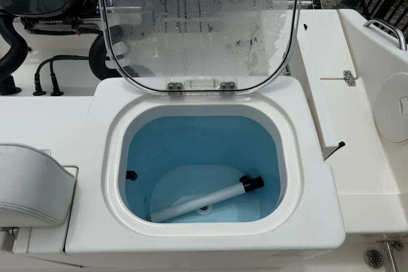 Slide: The Image of 2022 Cobia 240 Center Console livewell with open lid and visible plumbing. - 16