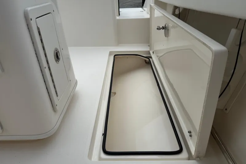 Slide: The Image of 2022 Cobia 240 Center Console storage compartment, open hatch, white interior, marine design. - 22