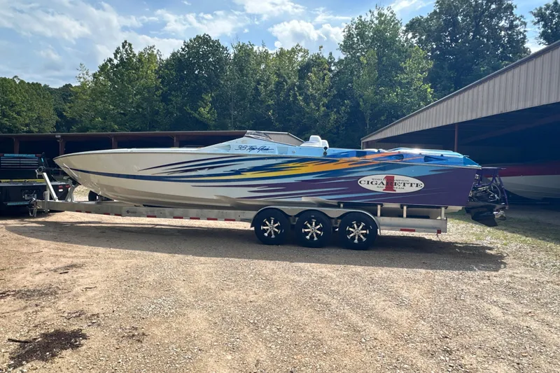 Slide: The Image of 2001 Cigarette 38 Top Gun boat on trailer, vibrant graphics, parked outdoors. - 2