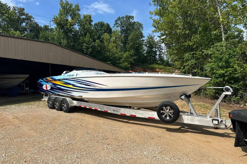 Slide: The Image of 2001 Cigarette 38 Top Gun boat on trailer, vibrant graphics, parked outdoors. - 5