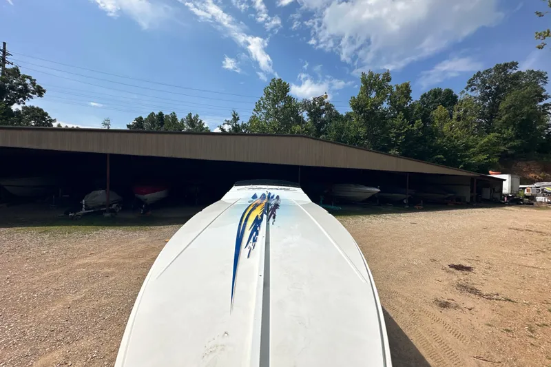 Slide: The Image of 2001 Cigarette 38 Top Gun boat in outdoor storage, surrounded by trees and clear sky. - 6
