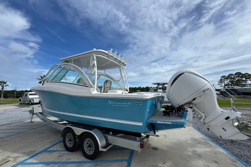Slide: The Image of 2023 Albemarle 27 Dual Console boat on trailer, blue hull, outboard motor, cloudy sky. - 10