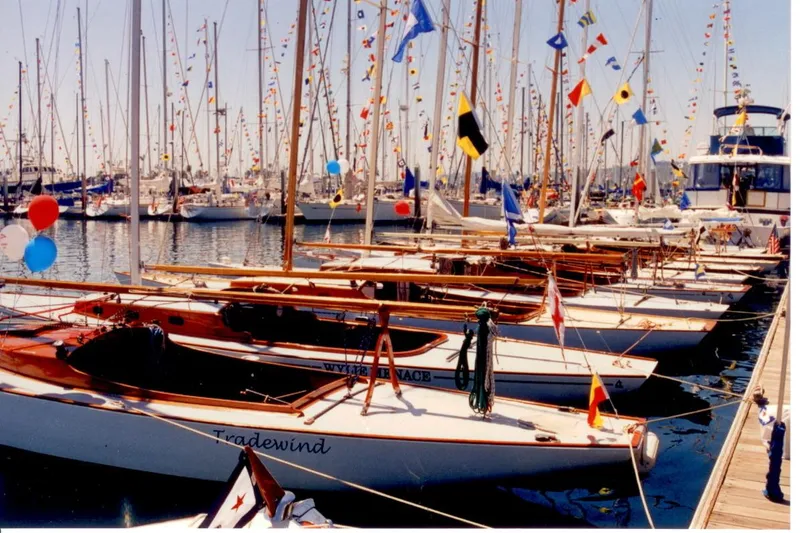 Slide: The Image of Sailboats docked at marina, featuring 1937 Kettenburg Pacific Class, adorned with colorful flags. - 3
