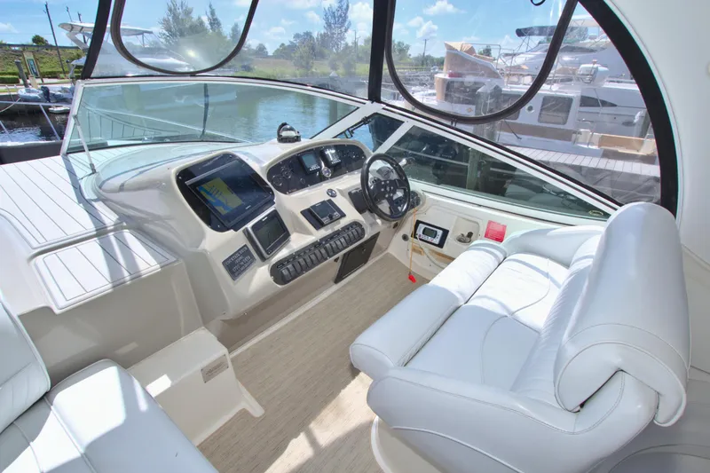 Slide: The Image of 2004 Cruisers Yachts 370 Express helm with modern controls and white seating. - 16