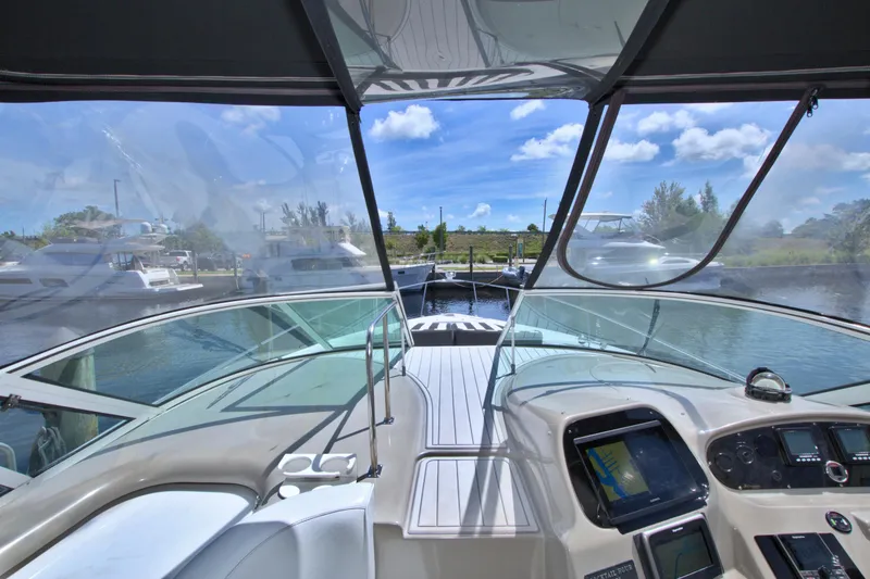 Slide: The Image of 2004 Cruisers Yachts 370 Express cockpit view with clear skies and marina backdrop. - 20
