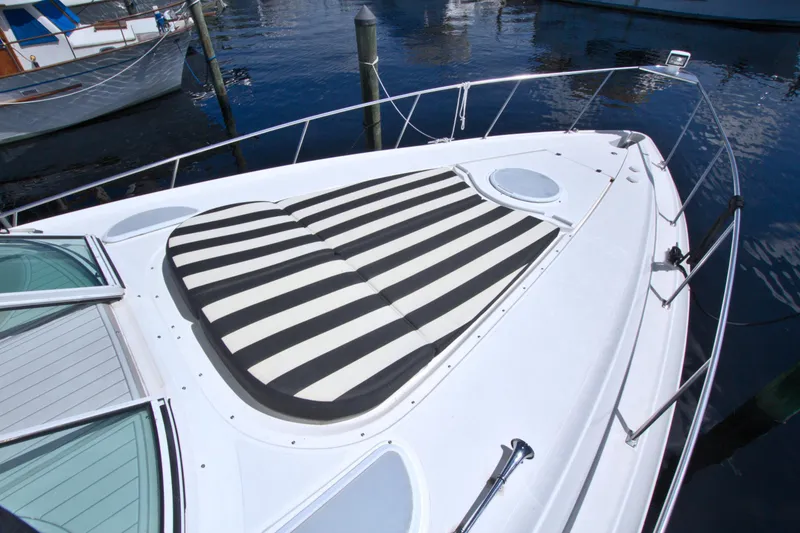 Slide: The Image of 2004 Cruisers Yachts 370 Express with striped sun pad on deck, docked at marina. - 21