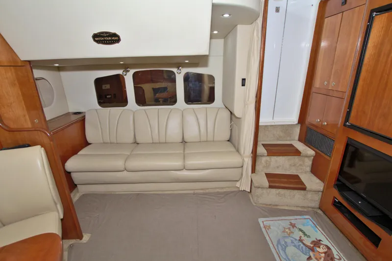 Slide: The Image of Interior of 2004 Cruisers Yachts 370 Express, featuring beige leather sofa and wooden cabinetry. - 34