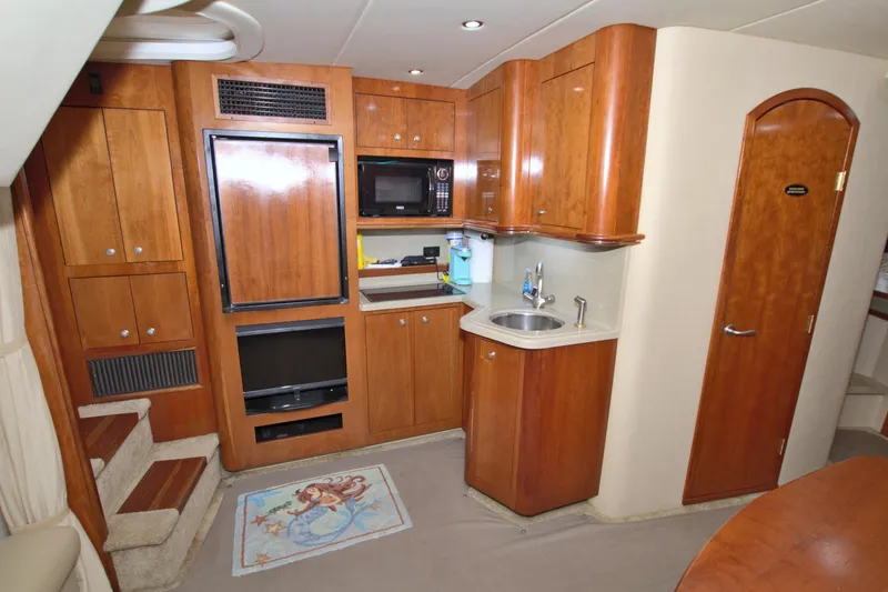 Slide: The Image of 2004 Cruisers Yachts 370 Express interior with kitchenette, wooden cabinets, and carpeted flooring. - 35