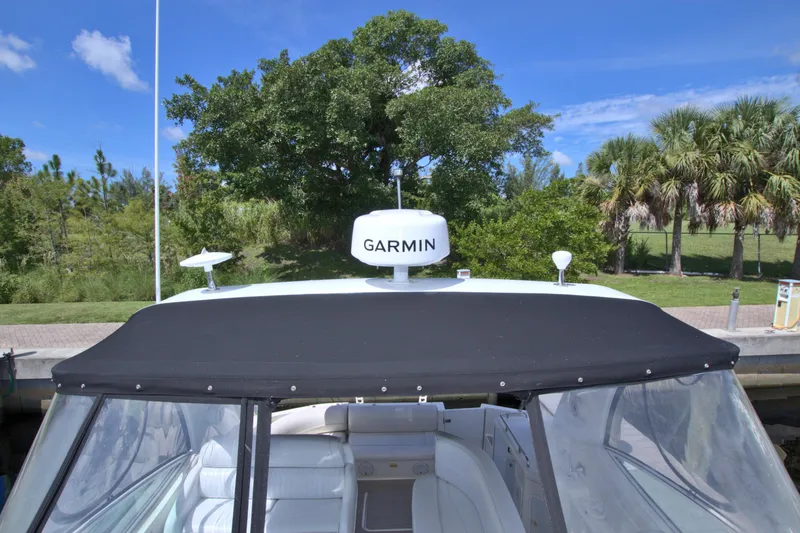 Slide: The Image of 2004 Cruisers Yachts 370 Express with Garmin radar, docked near lush greenery. - 27