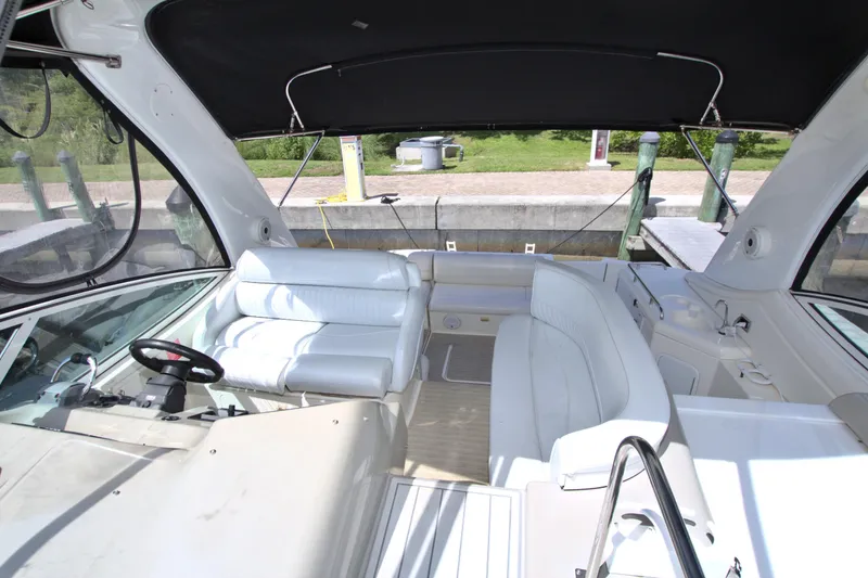 Slide: The Image of 2004 Cruisers Yachts 370 Express interior with white seating and helm, docked at marina. - 28