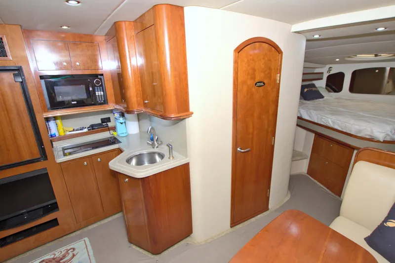 Slide: The Image of 2004 Cruisers Yachts 370 Express interior with kitchenette, sink, and cozy sleeping area. - 40