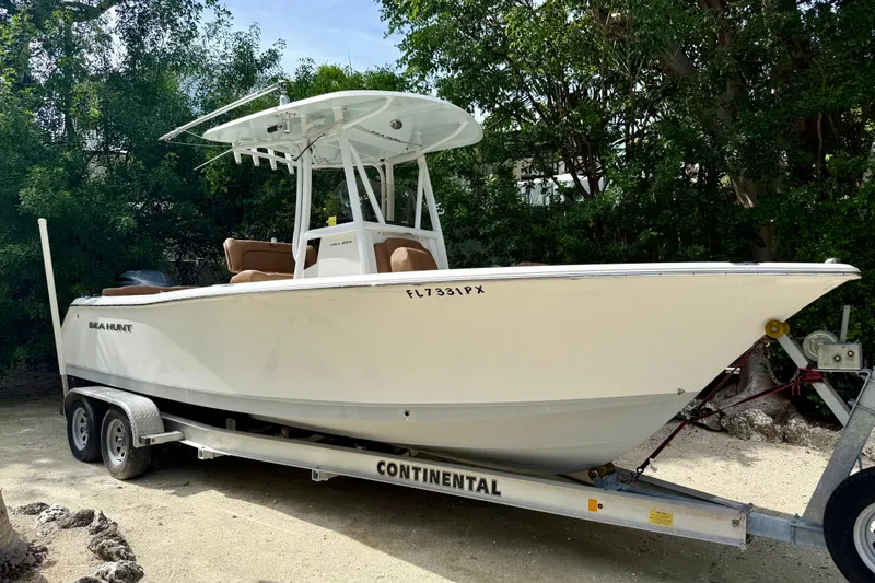 Slide: The Image of 2015 Sea Hunt Ultra 234 boat on trailer, surrounded by trees. - 0