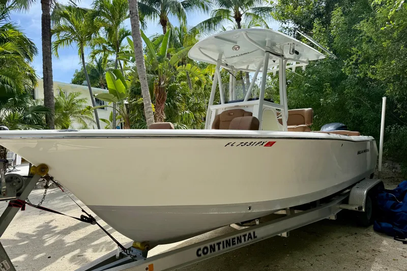 Slide: The Image of 2015 Sea Hunt Ultra 234 boat on trailer, surrounded by tropical palm trees. - 1