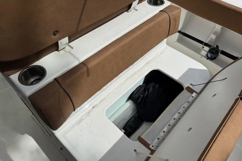 Slide: The Image of 2015 Sea Hunt Ultra 234 boat interior with storage compartment and brown seating. - 10