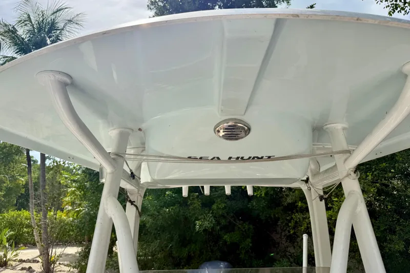 Slide: The Image of 2015 Sea Hunt Ultra 234 boat canopy with lush greenery background. - 11