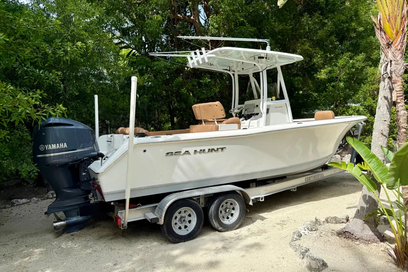 Slide: The Image of 2015 Sea Hunt Ultra 234 boat on trailer, surrounded by lush greenery. - 2