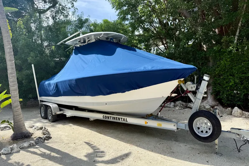 Slide: The Image of 2015 Sea Hunt Ultra 234 boat on trailer, covered with blue tarp, parked outdoors. - 24