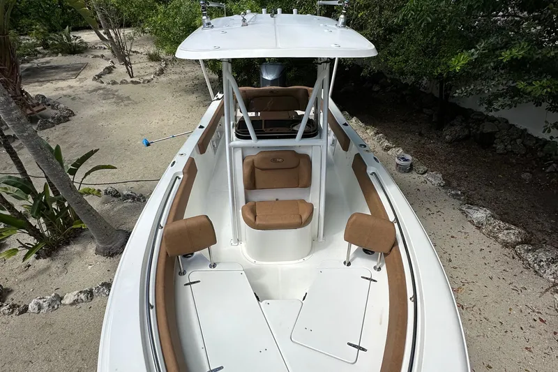Slide: The Image of 2015 Sea Hunt Ultra 234 boat with cushioned seating, parked on sandy ground. - 26