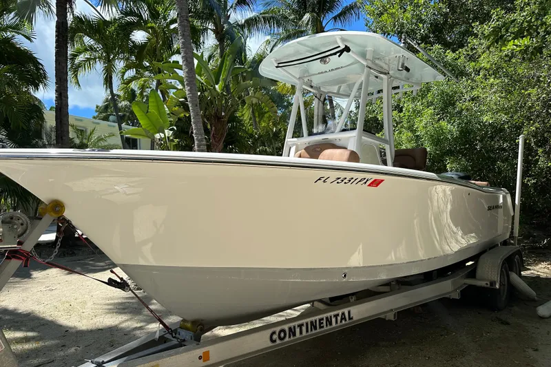 Slide: The Image of 2015 Sea Hunt Ultra 234 boat on trailer, surrounded by tropical trees. - 32
