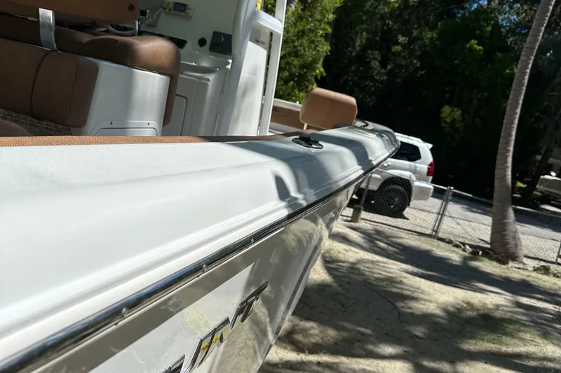 Slide: The Image of 2015 Sea Hunt Ultra 234 boat with brown seating, parked outdoors near trees and a vehicle. - 33