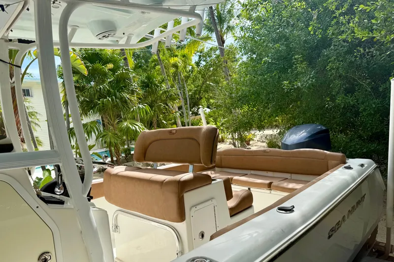 Slide: The Image of 2015 Sea Hunt Ultra 234 boat with tan seating, surrounded by lush greenery. - 7