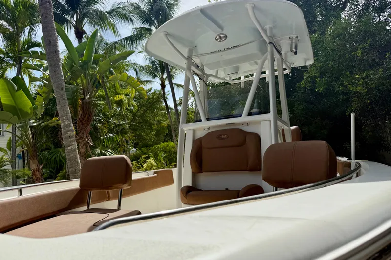 Slide: The Image of 2015 Sea Hunt Ultra 234 boat with brown seating, surrounded by lush tropical foliage. - 8